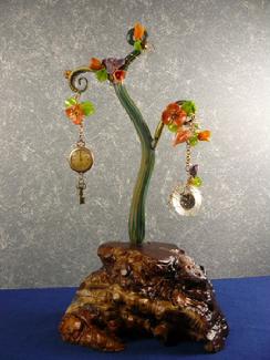 This sculpture is drapped in orange paper flowers with antique watches and a glass heart